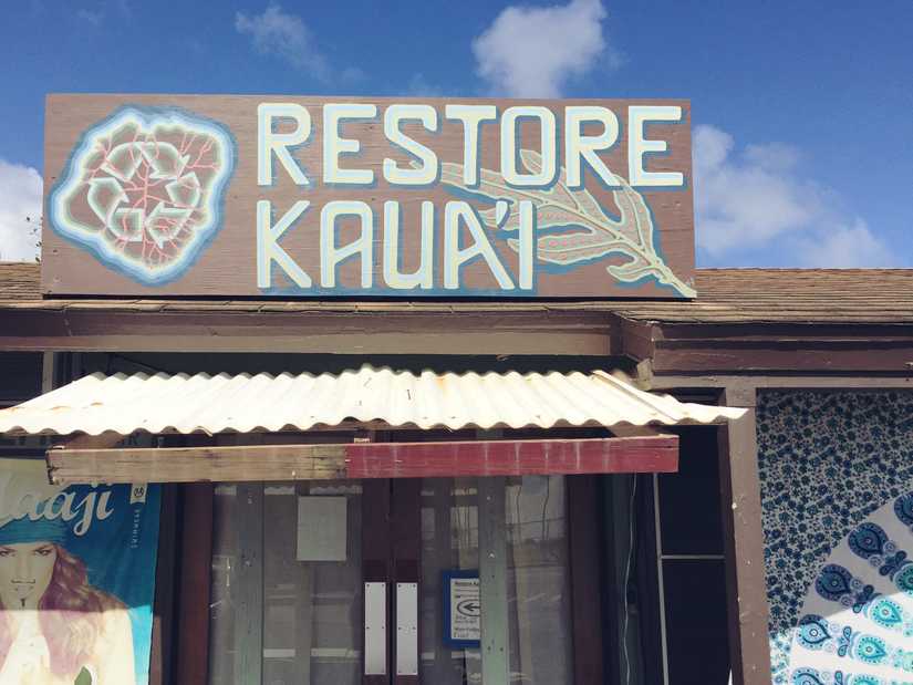 A sign mounted to the roof of a shop that reads "Restore Kaua'i"