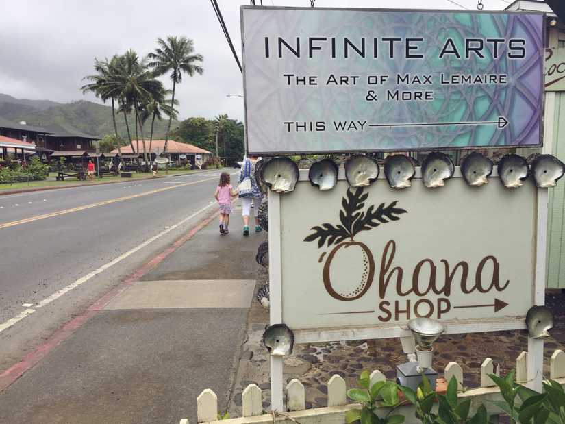 A printed sign right above a beautiful hand painted script sign reading "Ohana shop"