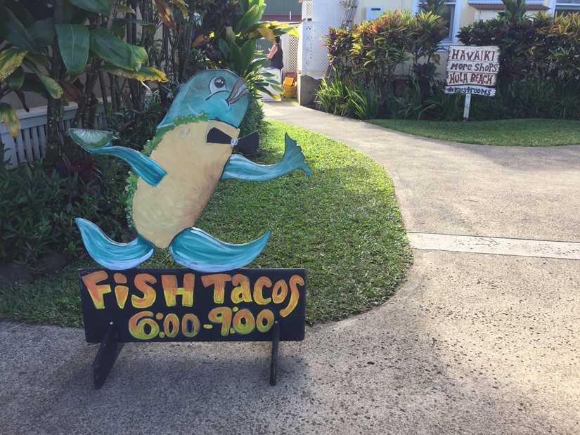 A wood cut out sign that has a fish server and reads "Fish Tacos" below