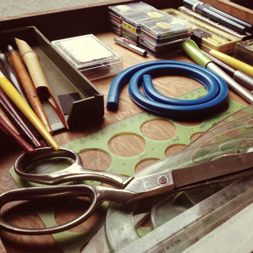 Drawer full of calligraphy and art supplies including pens, nibs, rulers, and scissors