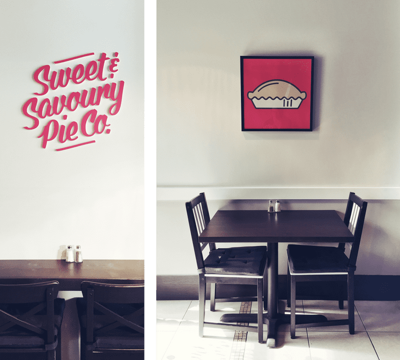 Pie shop interior showing CNC cut logo in red adhered to the wall above seating and a framed image of a pie icon above another set of table and chairs